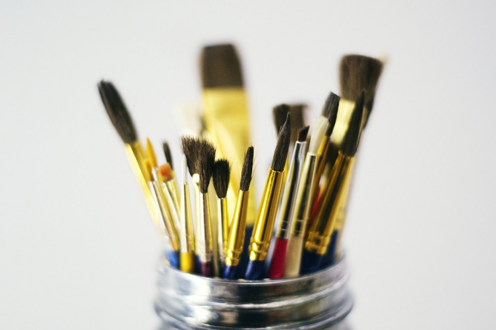 A glass jar holding a number of paintbrushes.