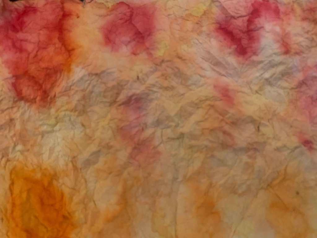 An abstract image of blended oranges, yellows, and bronze colors, on a wrinkled piece of paper.